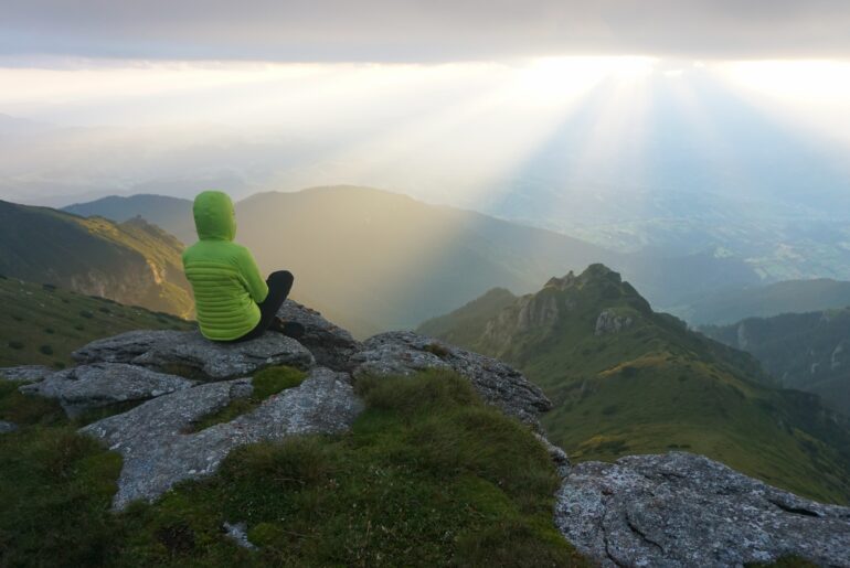 Mountain Life: A Life Above Dreams female-hiker-enjoying-view-from-summit-with-sun-s-rays-horizon